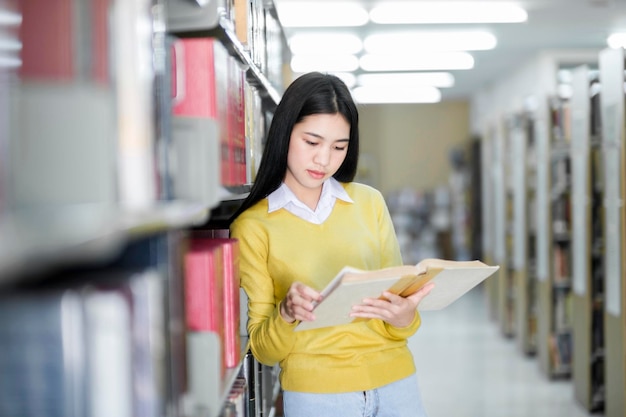 Aluno em pé e lendo livro na biblioteca