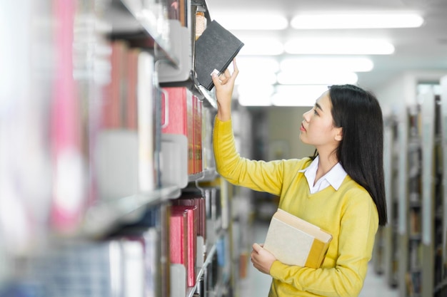 Aluno escolhendo e lendo livro na biblioteca