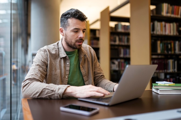 Foto aluno estudando aprendendo a preparação para o exame sentado no conceito de educação on-line da biblioteca moderna