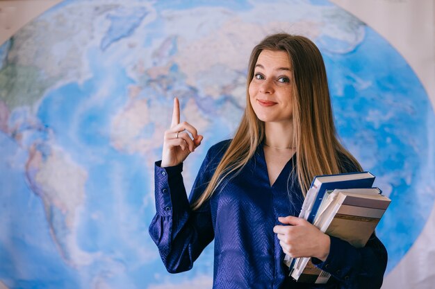 Foto aluno feliz com um mapa mundial na parede