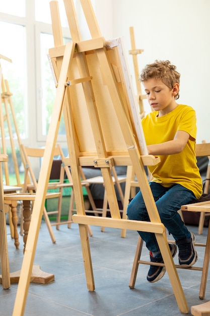 Aluno feliz enquanto pinta na escola de arte