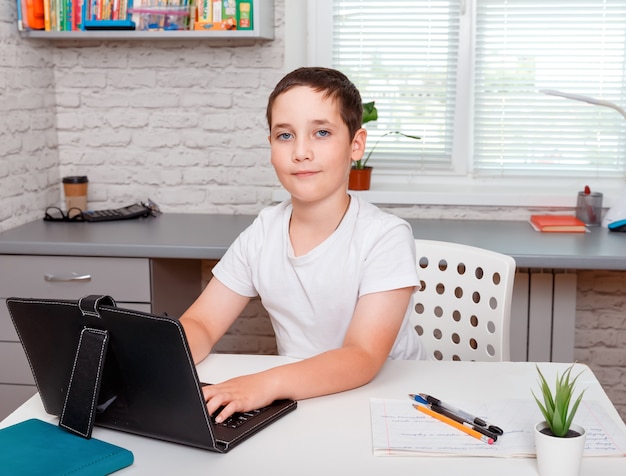 Aluno feliz fazendo lição de casa e sentado na mesa. educação escolar em casa