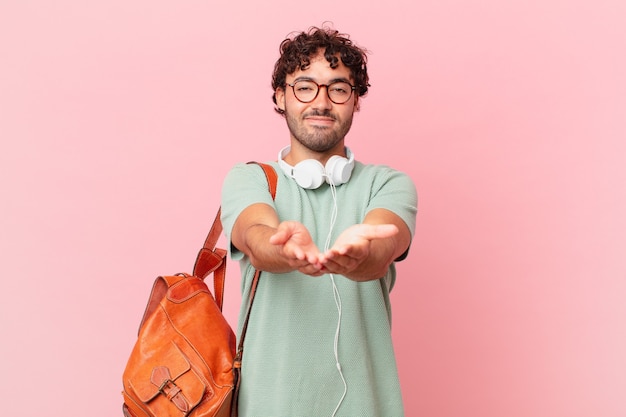 Aluno hispânico sorrindo feliz com um olhar amigável, confiante e positivo, oferecendo e mostrando um objeto ou conceito