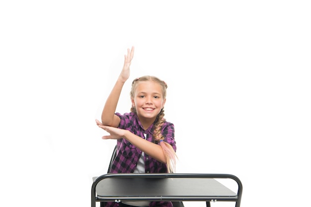 Aluno inteligente Aluno da escola primária Aluno pequeno levantando a mão na mesa isolada em branco Aluno recitando lição em classe