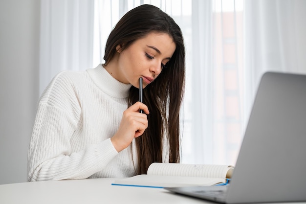 Aluno inteligente faz anotações no livro didático durante palestra on-line