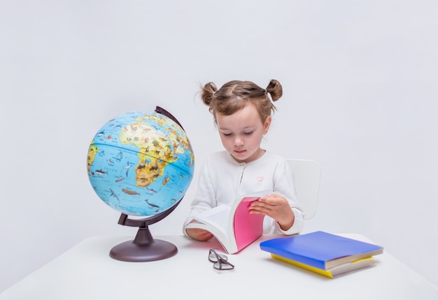 aluno pequeno senta-se à mesa e lê um livro em branco isolado com espaço para o texto.