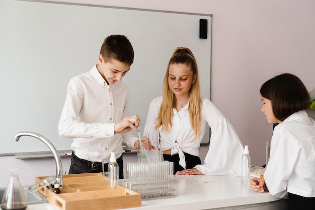 Aluno segurando frasco com líquido para experimentos em laboratório conceito de educação grupo de alunos estudando aula de química na escola