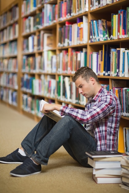 Aluno sério sentado na leitura do chão da biblioteca