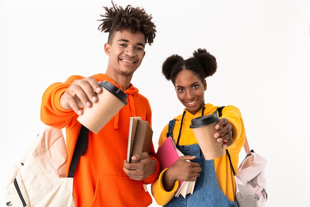 Foto alunos alegres com mochilas segurando cadernos, isolados sobre uma parede branca