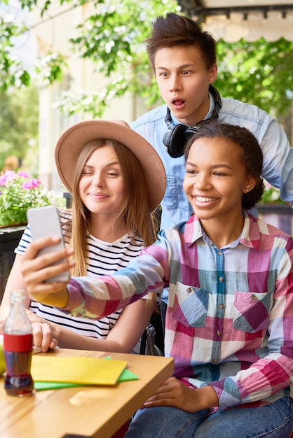 Foto alunos alegres, tendo selfie no café