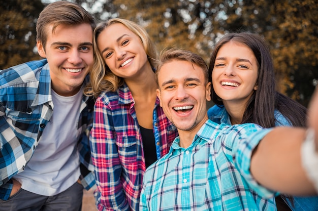 Alunos alegres tomando selfie no parque juntos.