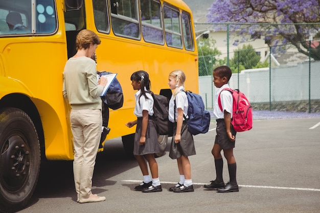 Foto alunos bonitos esperando para entrar no ônibus escolar