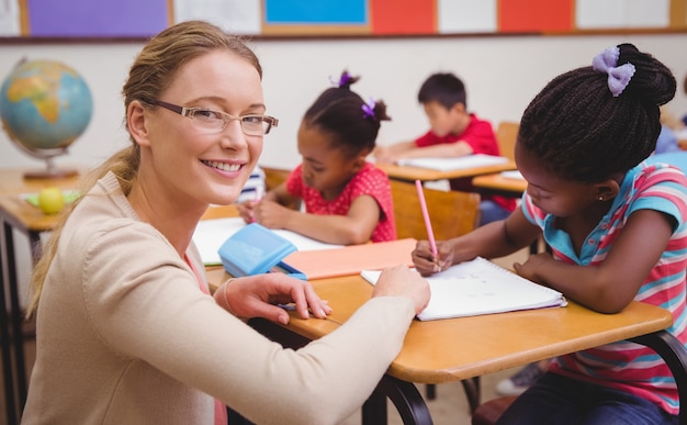 Foto alunos bonitos que escrevem na mesa na sala de aula