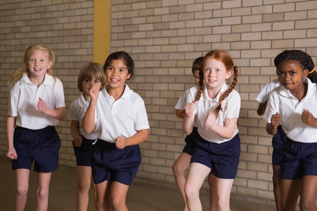 Alunos bonitos que se aquecem em uniforme pe