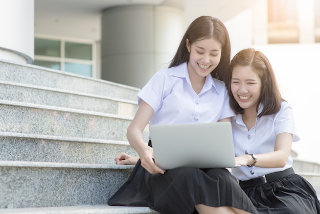 Alunos bonitos sentado e jogar computador na universidade, conceito de educação de pesquisa