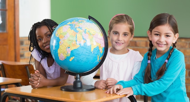 Alunos bonitos sentados em sala de aula com globo