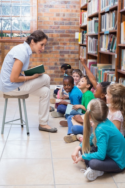 Alunos bonitos sentados no chão na biblioteca