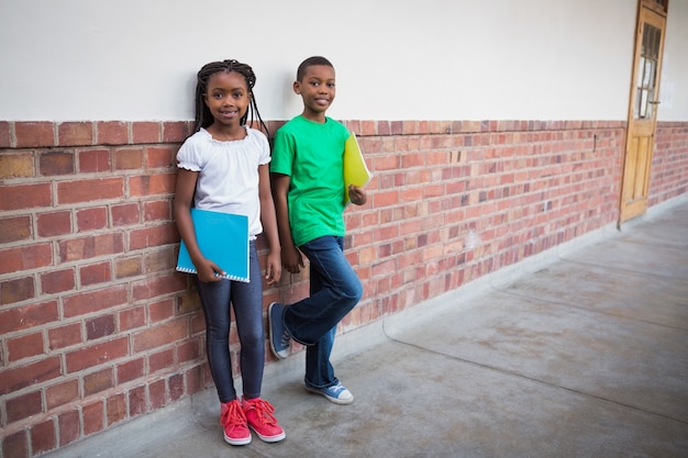 Alunos bonitos sorrindo na câmera no corredor