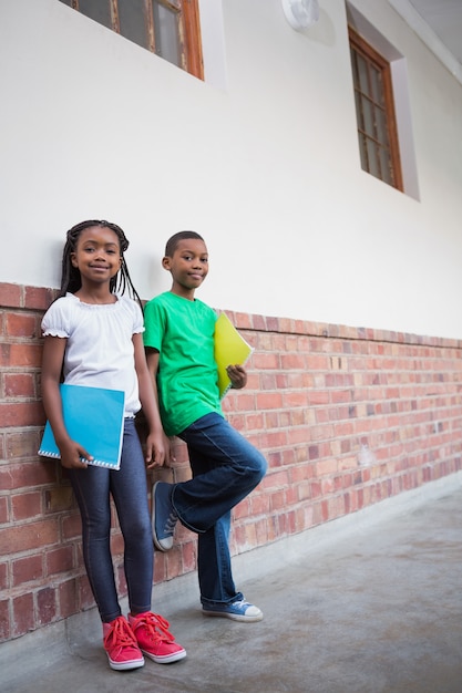 Alunos bonitos sorrindo para a câmera no corredor