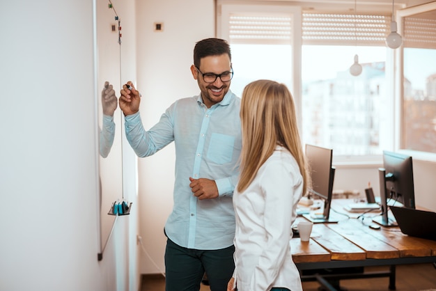 Alunos concentrados do homem e de mulher que estão e que escrevem no whiteboard.