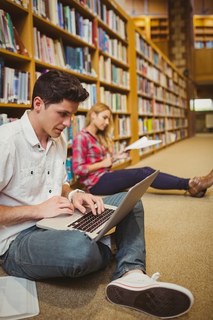 Alunos concentrados trabalhando no chão da biblioteca