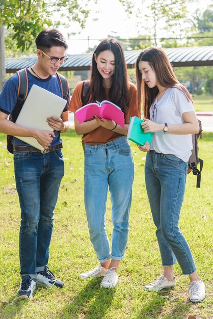 Alunos de amigos de grupo felizes em pé na faculdade lendo livro escolar juntos