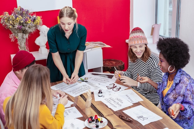 Alunos de ensino. professora de arte loira, atraente e inteligente, se sentindo ocupada enquanto ensina seus alunos