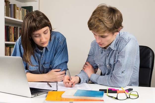 Alunos do sexo feminino e masculino trabalhando juntos em uma tarefa escolar ou profissional