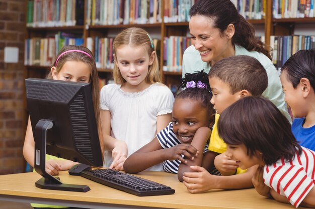 Foto alunos e professores na biblioteca usando computador