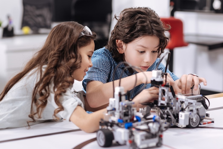 Foto alunos espertos trabalhando. alunos inteligentes felizes positivos sentados na aula e consertando o robô enquanto trabalhavam no projeto