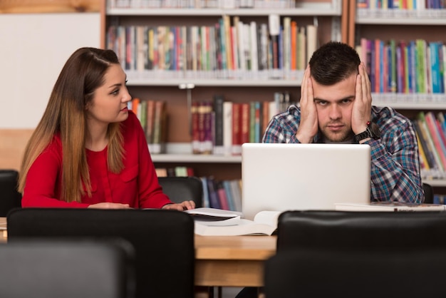 Alunos estressados no ensino médio sentados na mesa da biblioteca Profundidade de campo rasa