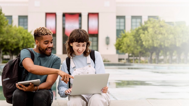 Alunos estudando em um laptop no campus da faculdade