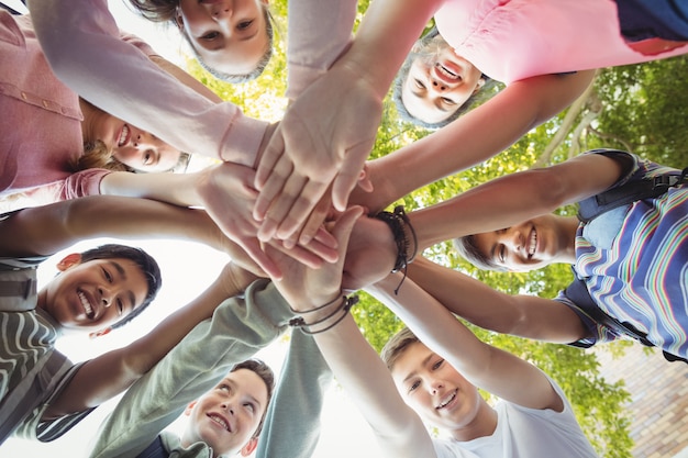 Alunos felizes formando pilha de mãos no campus