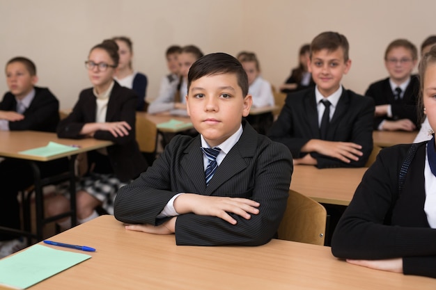 Alunos felizes sentados em uma mesa na sala de aula