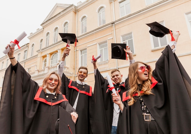 Alunos graduados felizes de baixo ângulo