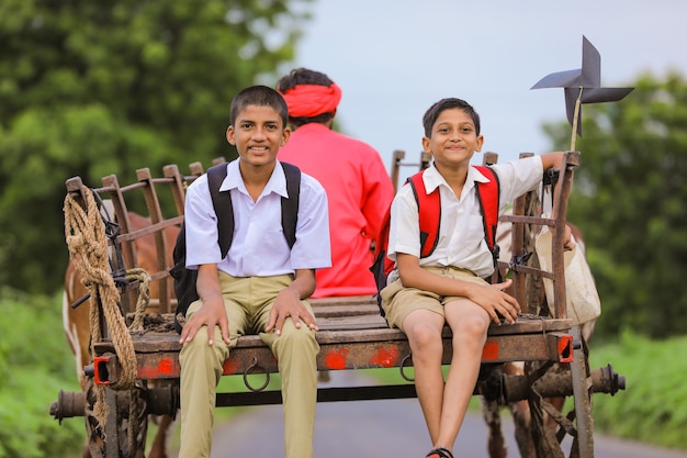 Alunos indianos fofos em um carro de boi