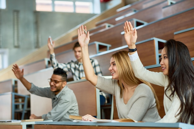 Alunos levantando as mãos na classe