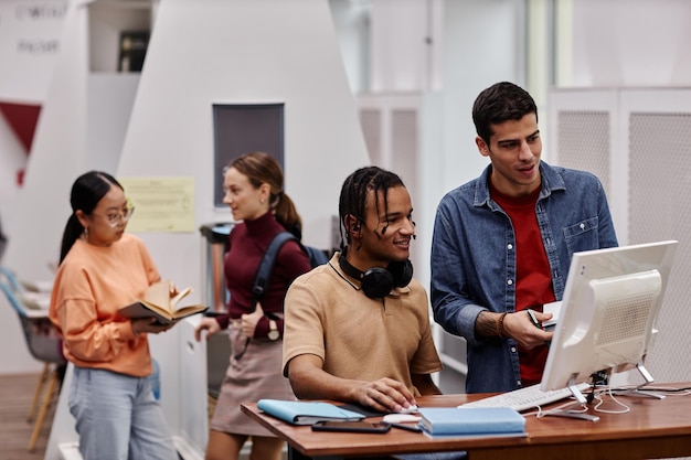 Alunos na biblioteca da faculdade focam em dois jovens usando computador