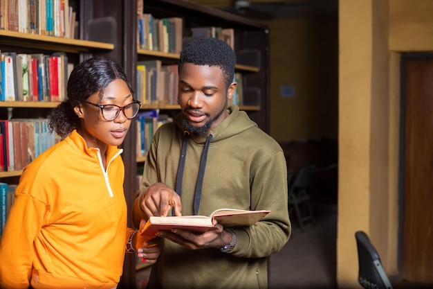 Alunos olhando para um livro na biblioteca