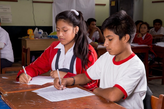 Alunos peruanos sul-americanos posando sozinhos e com seus professores realizando tarefas