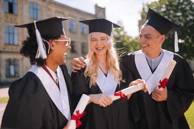 alunos próximos uns dos outros no campus, felizes por se formarem na universidade