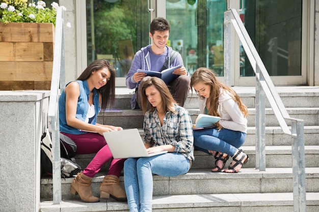 Foto alunos sentado nos degraus estudando