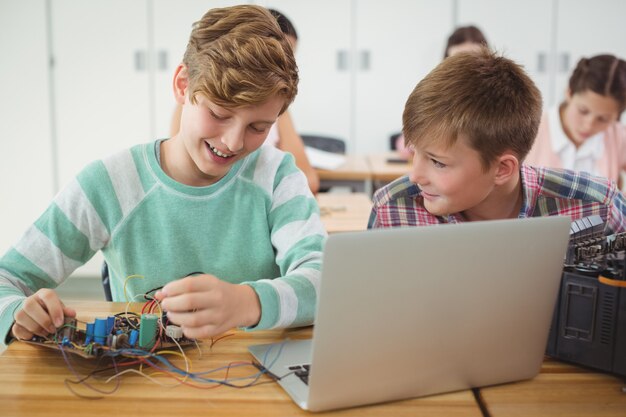 Alunos sorridentes trabalhando em projeto eletrônico em sala de aula