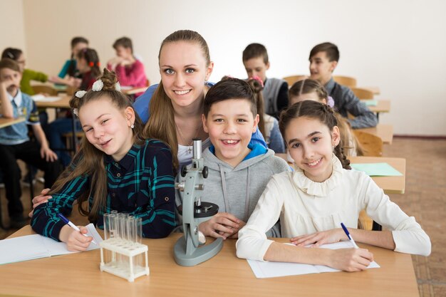 Alunos usando béqueres científicos e um microscópio na escola primária