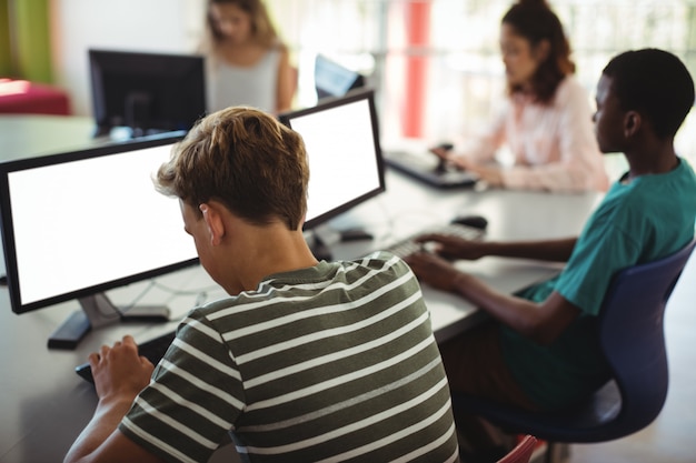 Alunos usando computador em sala de aula