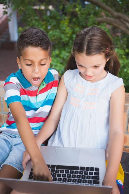 Alunos usando laptop no campus da escola