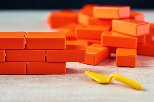 Foto alvenaria de blocos de brinquedo e colher de pedreiro. conceito de construção inacabada