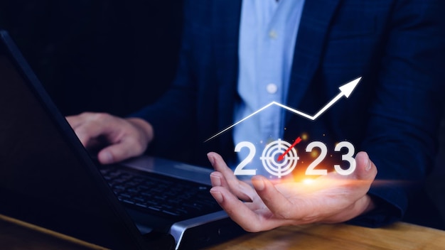Alvo de negócios e meta ícone 2023 mão apontando segurando tela virtual 2023 e seta para cima Comece o ano novo 2023 com uma meta plano plano de ação estratégia ano novo visão de negócios