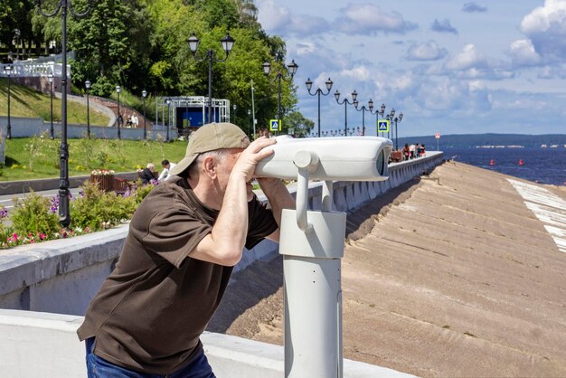 Am 19. Juni 2022 schaut in Tscheboksary ein Mann durch ein Fernglas nach Touristen auf der Uferböschung