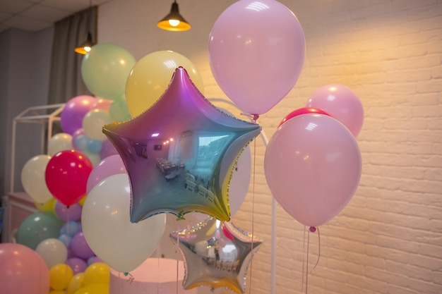 Am Geländer der Veranda sind Ballons befestigt. Eröffnung des Ladens. Cremefarbene Wand, rote Treppe. Helles Sonnenlicht und Schatten. Festlicher Straßenhintergrund.